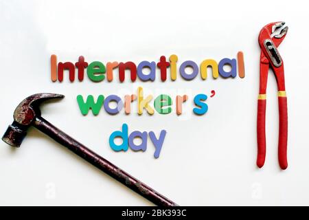 Internationaler Workers` Day Text in mehrfarbiger Schrift auf weißem Hintergrund mit Baureparaturwerkzeugen. Schild „Labor Day Concept“. Tag der internationalen Arbeiter.` Stockfoto